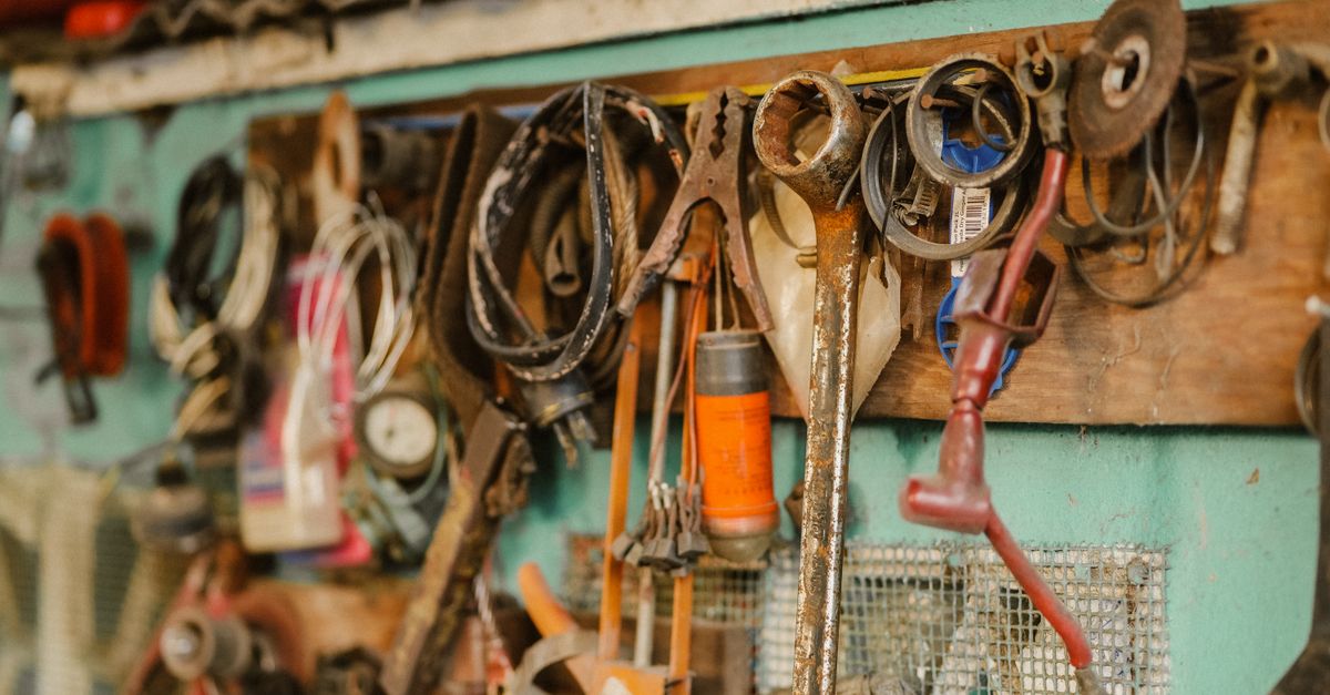 A collection of vintage tools hanging on a workshop wall, showcasing a rustic and messy appeal.